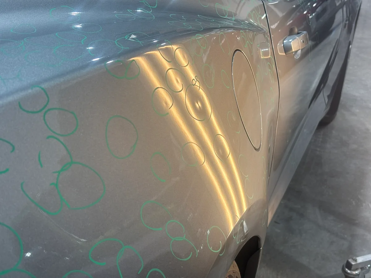 Dense hail dents marked across a vehicle quarter panel before paintless dent repair in Olathe, KS