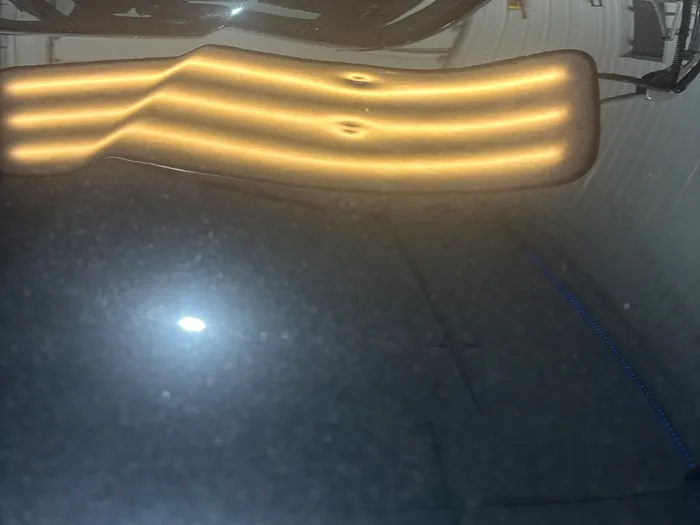 Line-board reflections revealing two distinct hail dents in a dark car hood.
